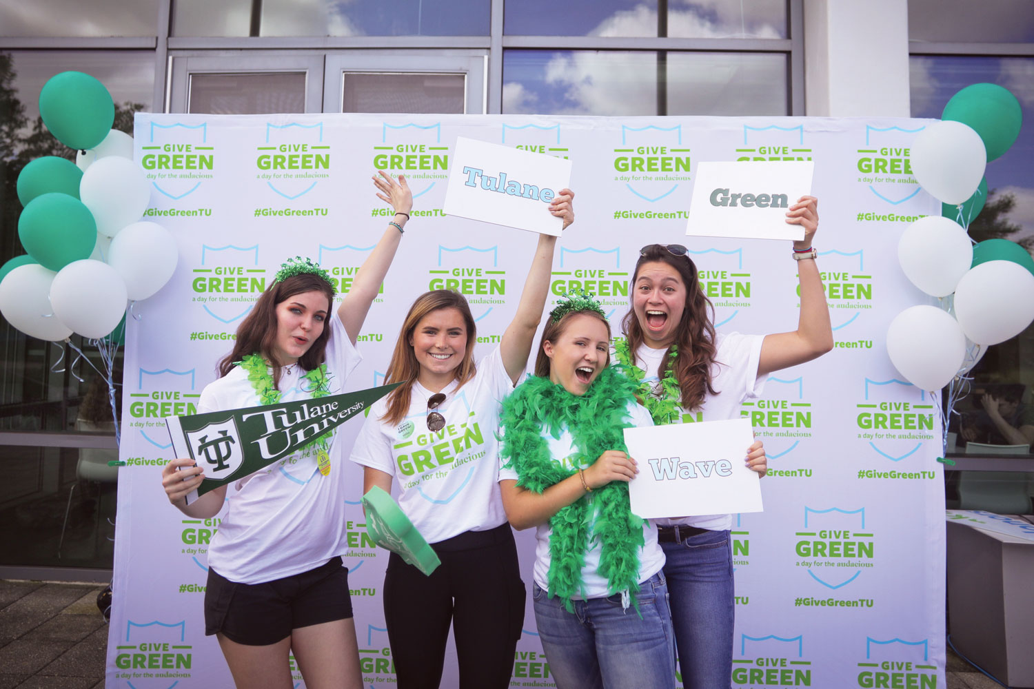 Students cheering in front of a backdrop Give Green 2019