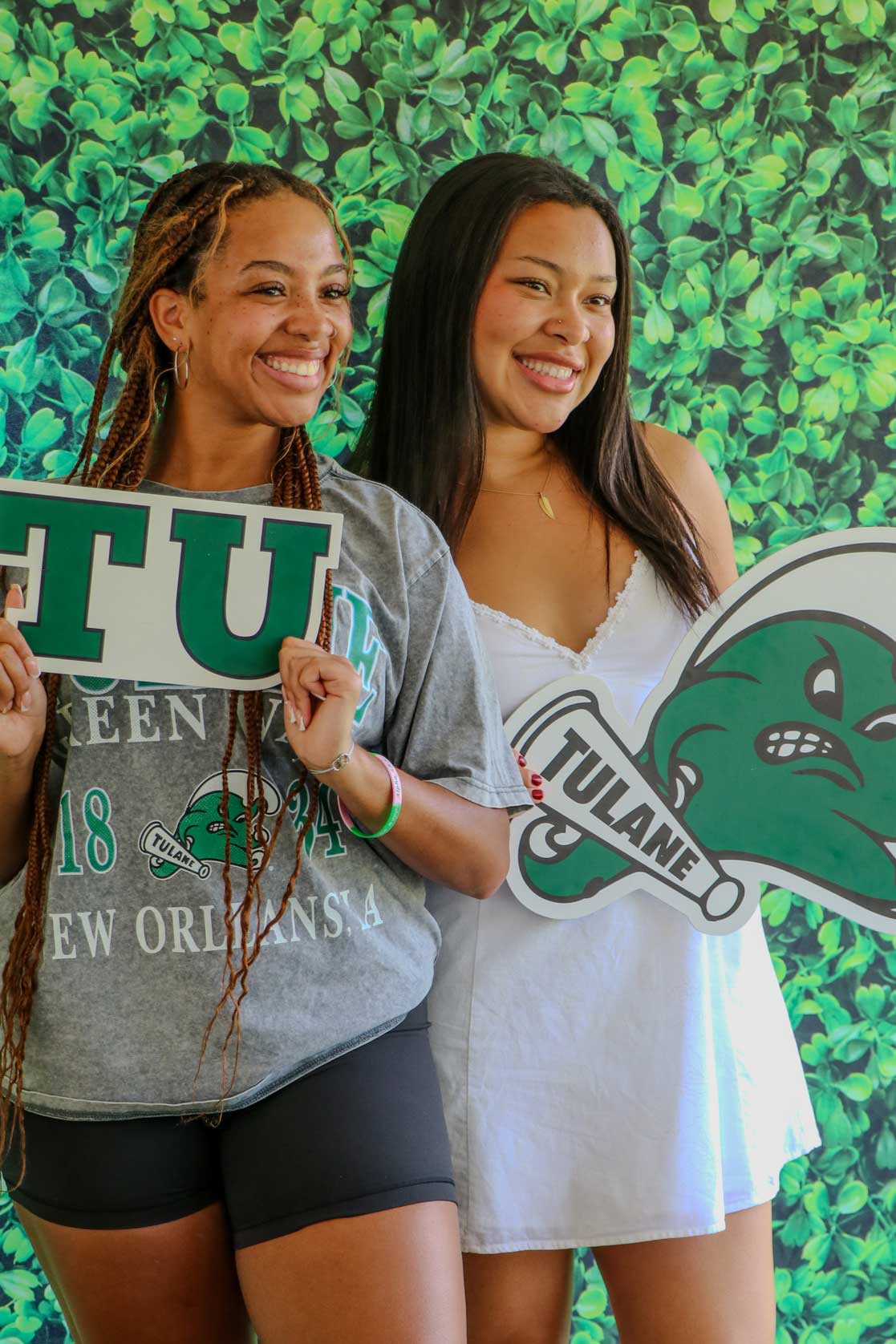 Tulane students holding signs in front of green backdrop