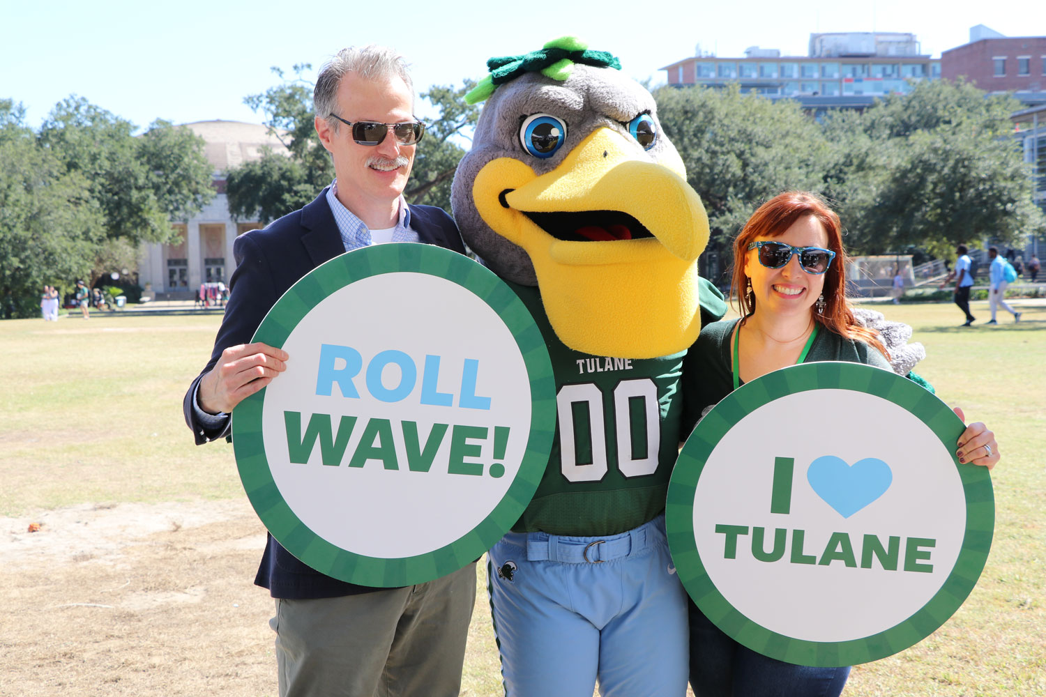 Tulane staff holding Roll Wave and I love tulane signs