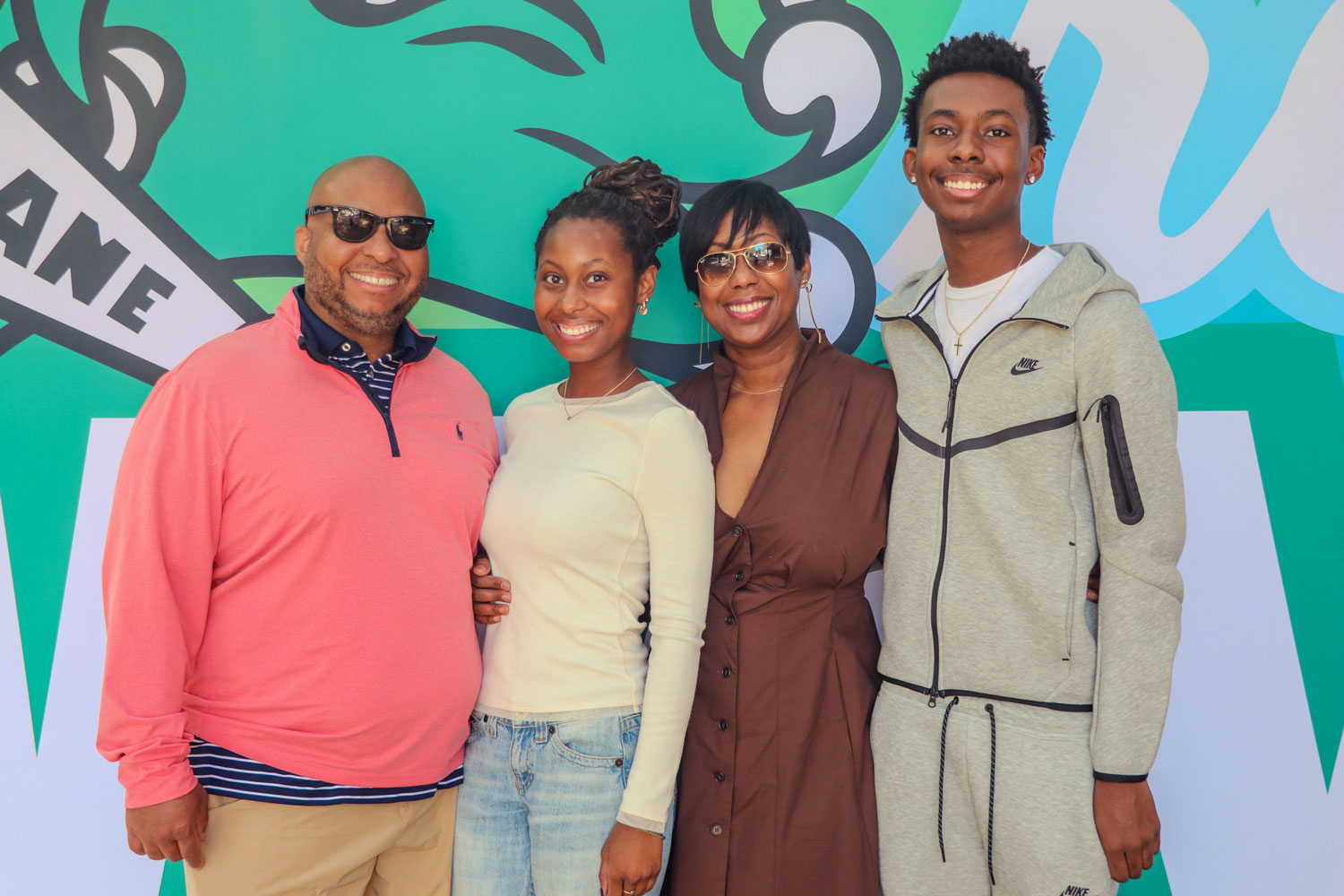 Family smiling in front of a Tulane angry wave sign