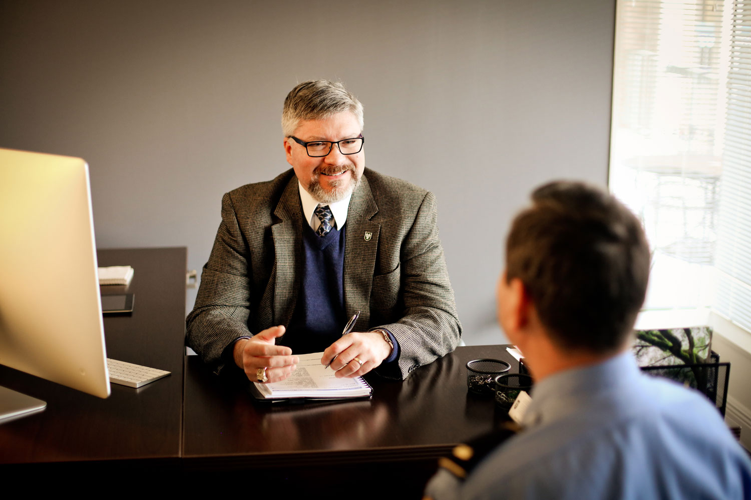 Man behind desk talking to a police officer
